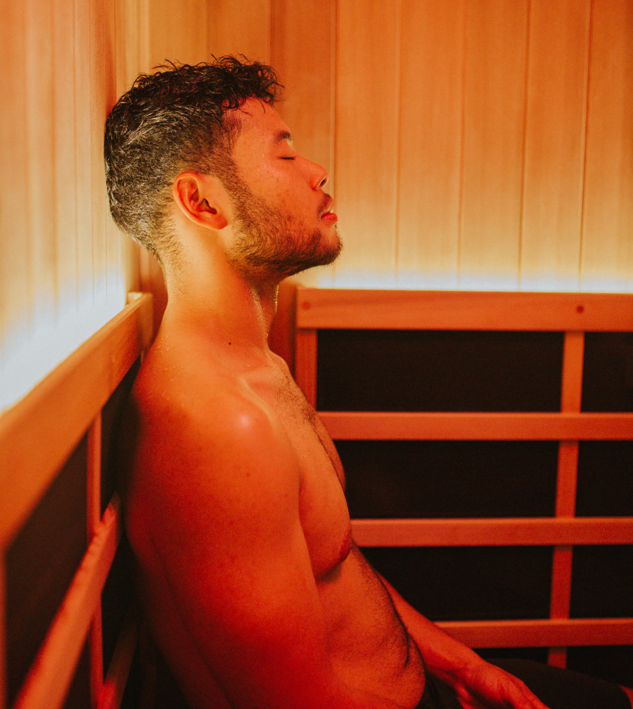 Person sitting in a private infrared sauna with red light