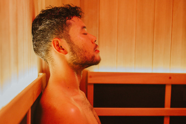 Person sitting in a private infrared sauna with red light