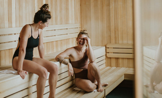 Two women sitting in the sauna talking and laughing