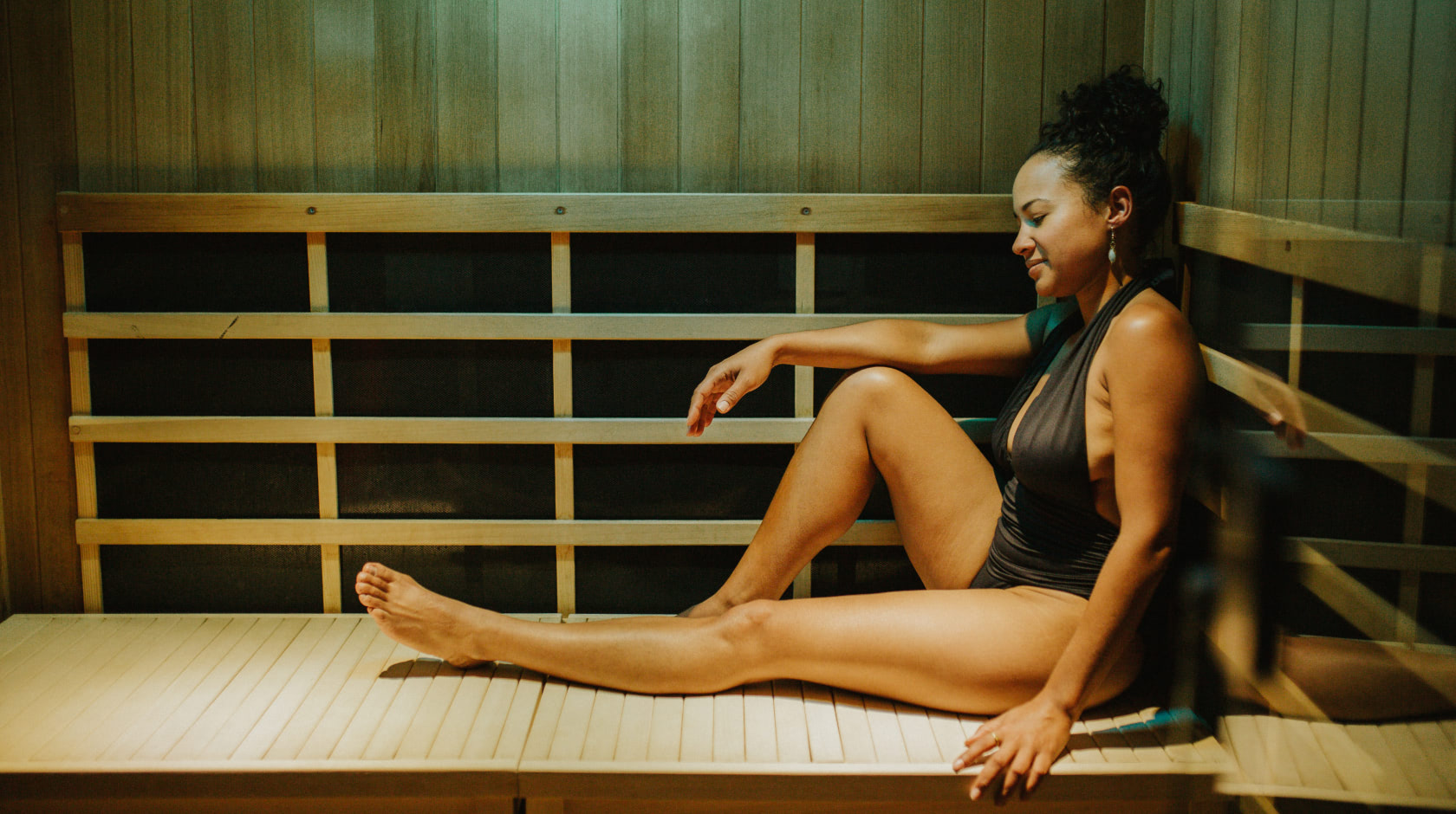 Woman sitting in an infrared sauna with green light