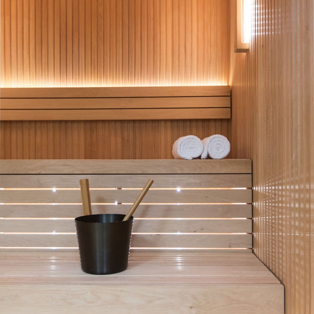 Sauna bucket and fresh towels sitting on the bench of the Libera cabin sauna