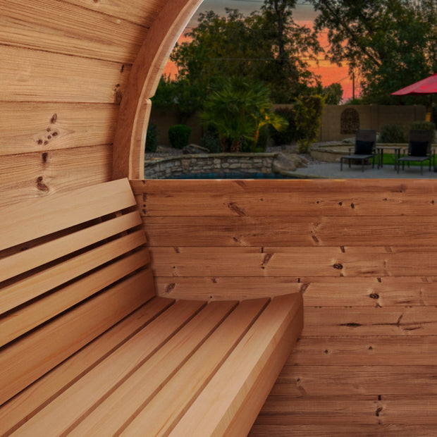 Inside view of the SaunaLife barrel sauna looking out of the rear window at a sunset view