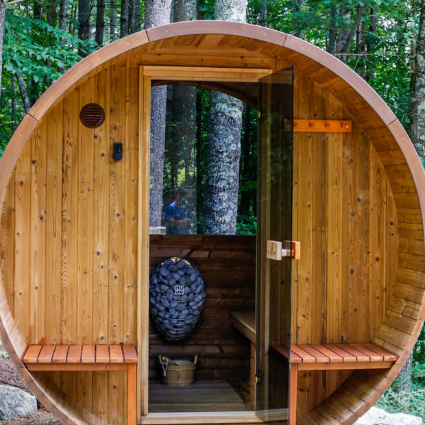 Barrel sauna with front porch, door open looking through to the panoramic backwall window and the forest view beyond