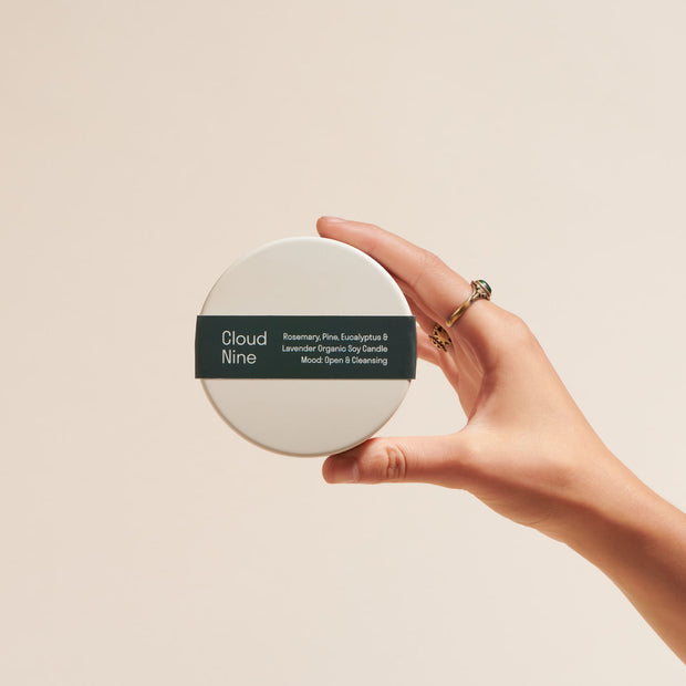 Person holding the mini Cloud Nine Organic Soy Wax Candle to show the top label
