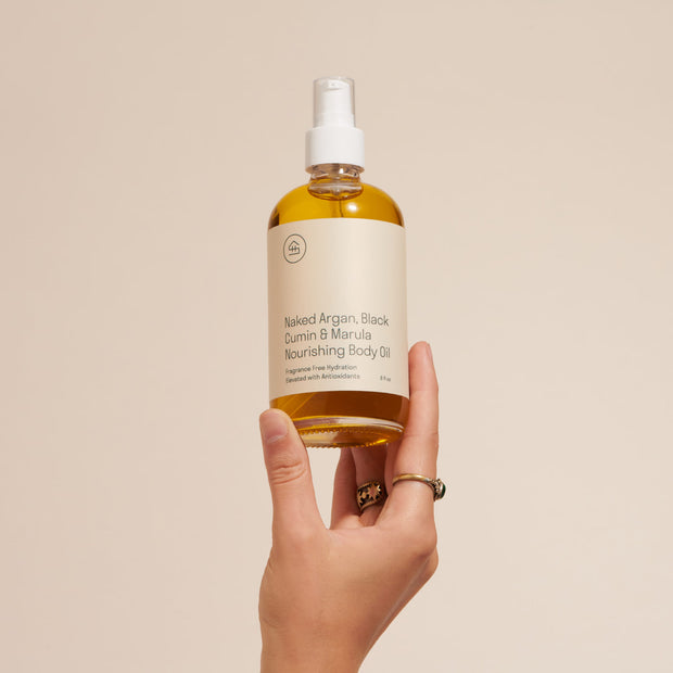 Person holding full size Naked Argan & Marula Body Oil